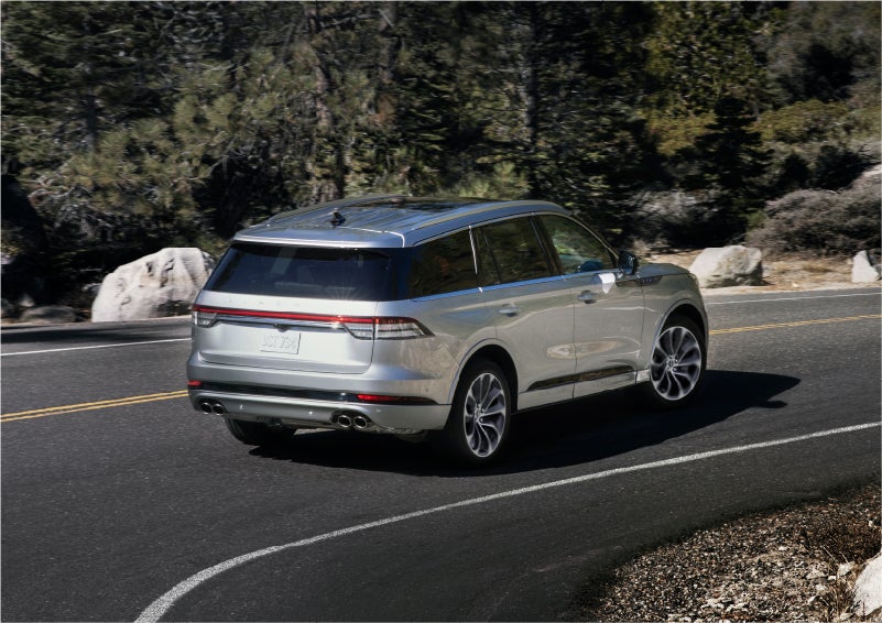 A 2023 Lincoln Aviator® Grand Touring model is shown being driven on a tight turn of a mountain road | Vision Lincoln in Wahpeton ND