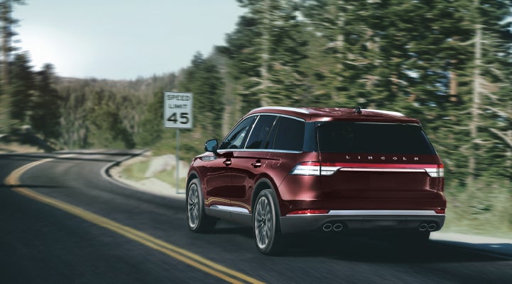 A 2024 Lincoln Aviator® SUV is being driven on a winding mountain road | Vision Lincoln in Wahpeton ND