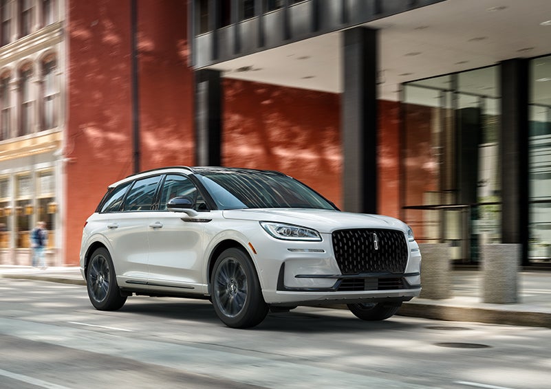 The 2024 Lincoln Corsair® SUV with the Jet Appearance Package and a Pristine White exterior is parked on a city street. | Vision Lincoln in Wahpeton ND